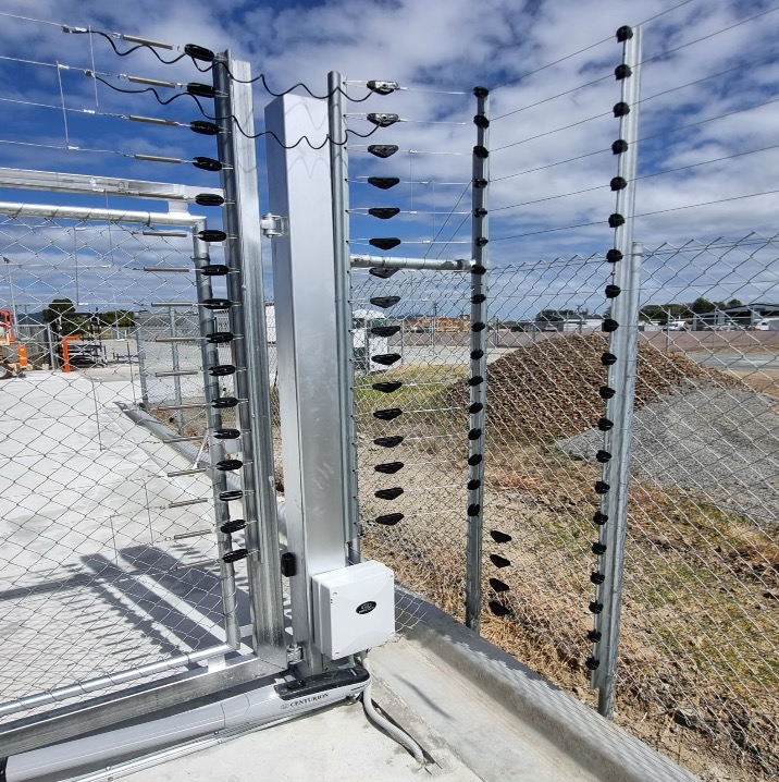 Electric fencing energizer and wall-top fence installation on a gate structure