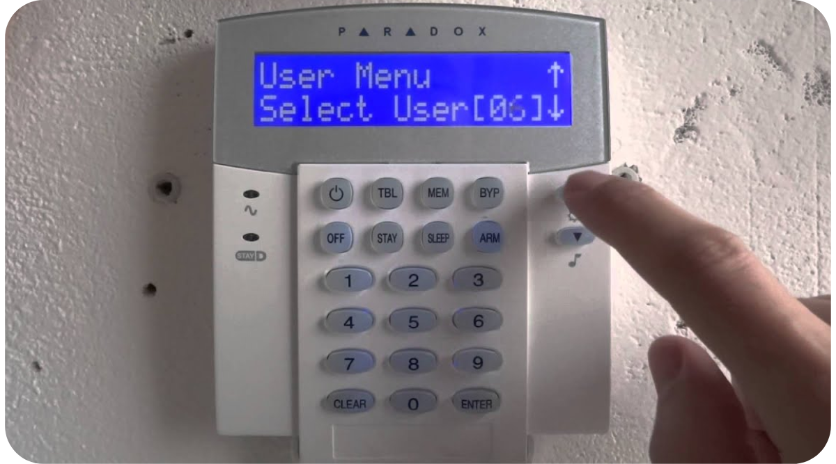 Alarm system keypad with LCD user menu being programmed on a wall